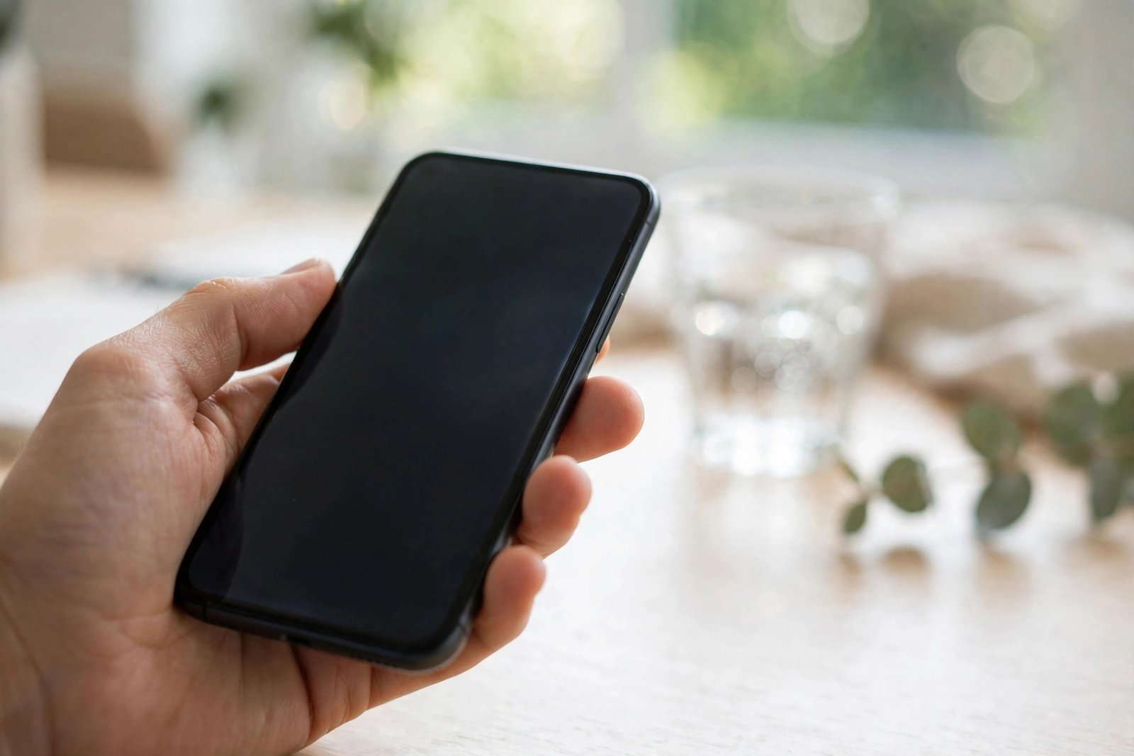 Hand holding a smartphone with a dimmed screen to save battery power