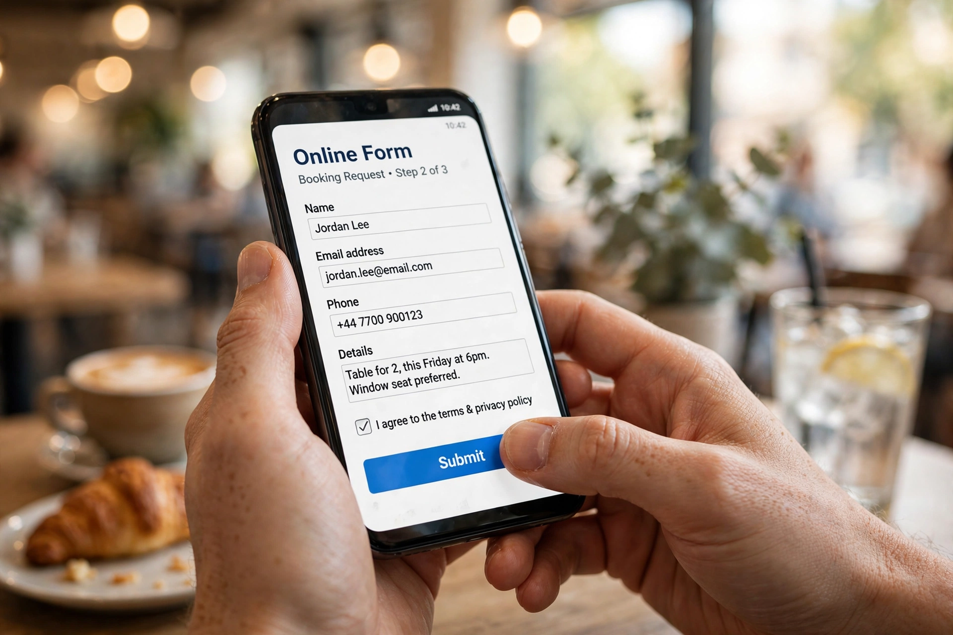 Hands holding a smartphone and filling out an online form in a bright cafe