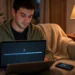 Young man downloading a video on a laptop with a download progress bar on screen